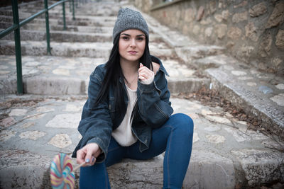 Portrait of young woman having lollipop while sitting on steps