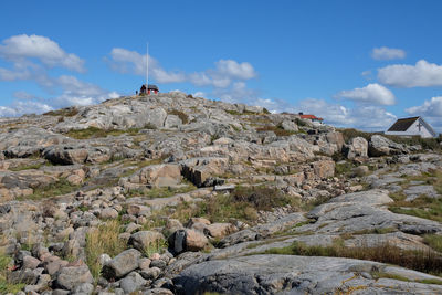 Distant view of houses on rocky hill against sky