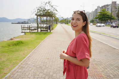 Portrait of smiling relaxed fashion woman walking on florianopolis promenade, santa catarina, brazil