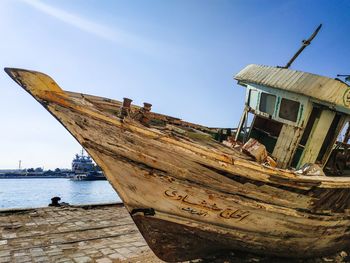 Low angle view of abandoned boat on beach against sky