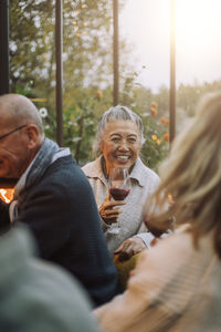 Happy senior woman holding wineglass at dinner party