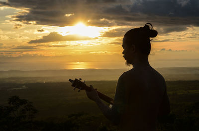 Silhouette man playing against sky during sunset