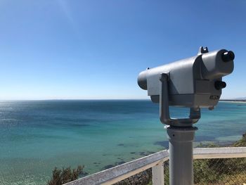 Close-up of coin-operated binoculars by sea against clear blue sky