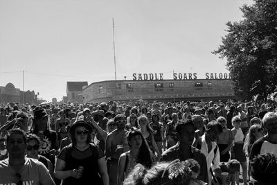 Crowd standing in front of people against clear sky