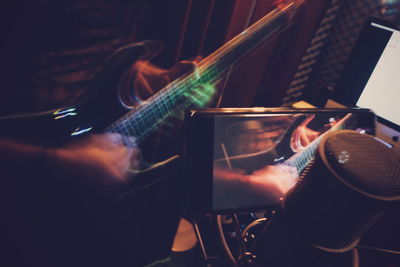 Close-up of mobile phone recording musician playing guitar