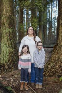 Portrait of mother with her two children in forest.