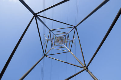 Low angle view of electricity pylon against clear blue sky