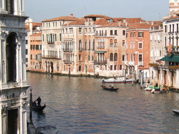 Boats in canal by buildings in city