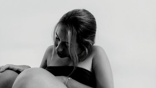 Close-up of young woman sitting against white background