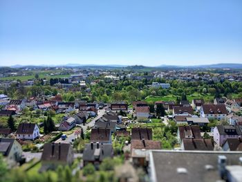 High angle view of houses in town against clear blue sky