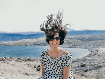 Portrait of young woman wearing sunglasses standing on beach