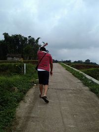 Rear view of woman on grass against sky