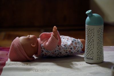 Close-up of toy baby by bottle on bed