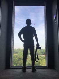 Silhouette man standing against window