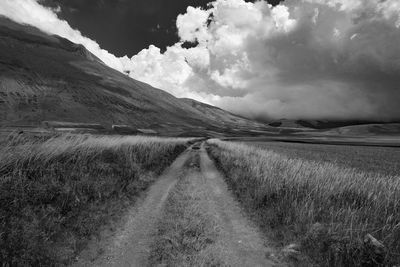 Road amidst field against sky