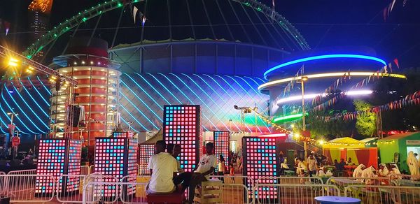 People in illuminated amusement park at night