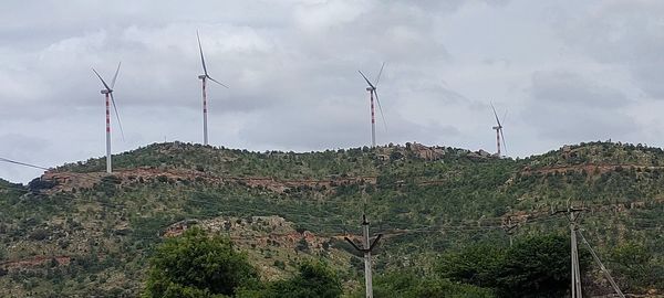 Low angle view of wind turbines on land against sky