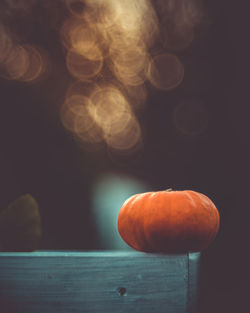 Close-up of an isolated little pumpkin on a dark background with yellow bokeh light