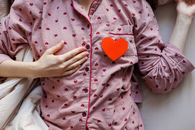 Midsection of woman holding heart shape