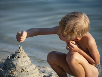 Cute boy making sandcastle at lakeshore