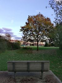 Empty bench in park against sky