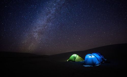 Illuminated tents against sky at night