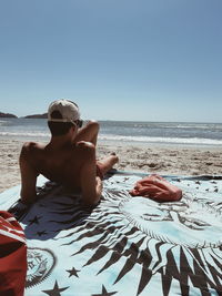 Man wearing hat on beach against clear sky