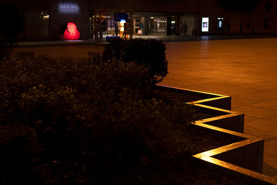 Illuminated street light by building at night