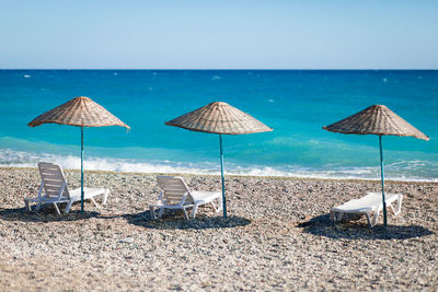 Deck chairs on beach against sky