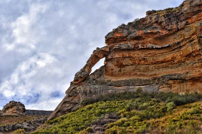 Low angle view of rock formations against cloudy sky