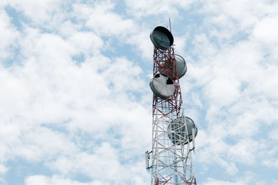 Low angle view of communications tower against cloudy sky