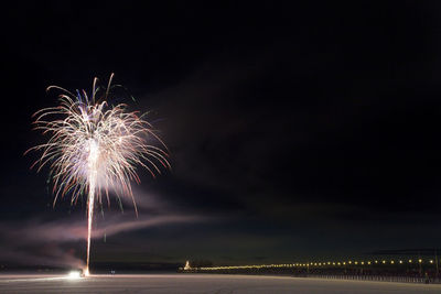 Firework exploding over landscape against sky at night