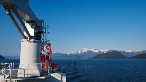 Crane by sea against clear blue sky
