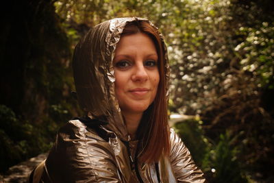 Portrait of smiling woman wearing raincoat in forest