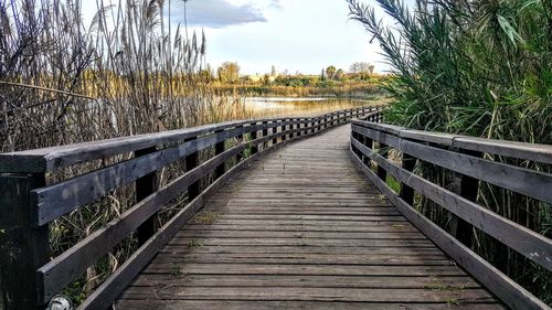 Surface level of boardwalk on footbridge against sky