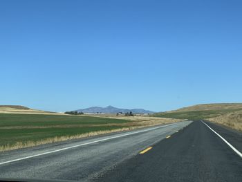 Road passing through landscape against clear sky