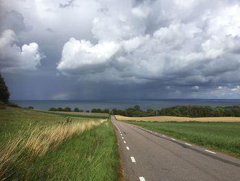 Country road against cloudy sky