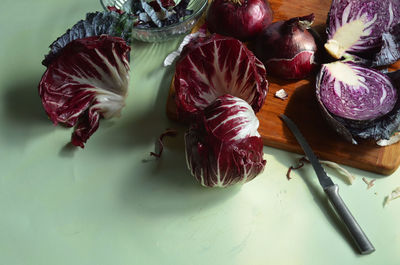 Radicchio, knife, cut red cabbage, red onion, on bamboo cutting board on light green surface
