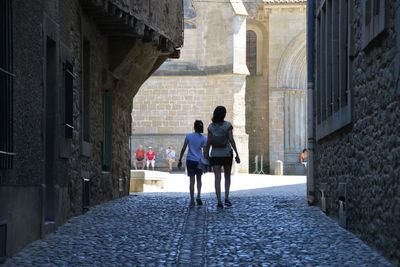 Rear view of people walking on street amidst buildings in city