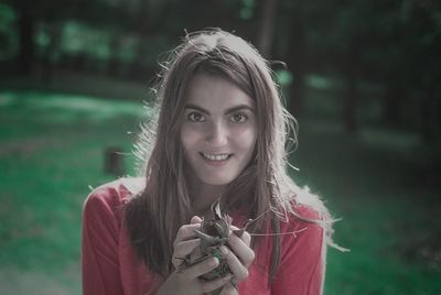 Portrait of a smiling young woman holding outdoors