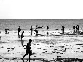 Silhouette people playing on beach against clear sky
