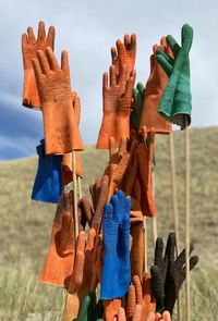 Close-up of multi colored umbrellas on field against sky