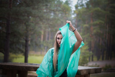 Woman wearing raincoat while standing against trees