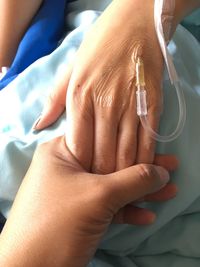 Cropped image holding patient hand on bed