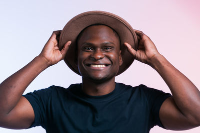 Portrait of young man wearing hat against gray background