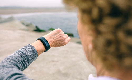 Woman checking smart watch while standing on pier