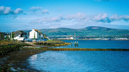 Scenic view of sea by buildings against sky