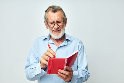 Portrait of senior man using mobile phone against white background