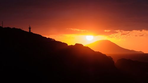 Scenic view of silhouette mountains against orange sky
