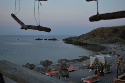 Seats with parasols at beach against sky during sunset